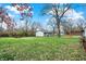 Spacious yard featuring a two-car garage, lawn area, and wood deck under a tree against a blue sky at 7609 Camby Rd, Indianapolis, IN 46113