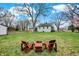 Backyard view with a patio set on a lawn area under a large tree, blue skies, and surrounding greenery at 7609 Camby Rd, Indianapolis, IN 46113