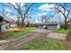 Exterior view of a backyard featuring a two-car garage, wood deck, large yard with a tree, and driveway at 7609 Camby Rd, Indianapolis, IN 46113