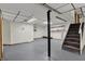 Spacious basement featuring a gray floor, a black support beam, stairs, shelving, and paneled ceiling with recessed lighting at 7609 Camby Rd, Indianapolis, IN 46113