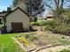 Landscaped backyard with a garden bed, mature trees, and the back of a building with a porch at 1030 Pamela Dr, Plainfield, IN 46168
