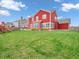 View of a two-story home with red siding, large backyard with grass and patio area at 10603 Hinterland Dr, Fishers, IN 46038