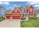 Aerial view of a two-story home with red siding, attached garage, and a lush green lawn at 10603 Hinterland Dr, Fishers, IN 46038