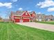 View of a two-story home with red siding, attached garage, and a lush green lawn at 10603 Hinterland Dr, Fishers, IN 46038
