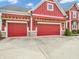 Three-car garage with decorative wood accents and red doors, enhances curb appeal of red siding home at 10603 Hinterland Dr, Fishers, IN 46038
