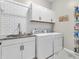 Well-lit laundry room with modern washer and dryer, sink, and ample storage space at 10603 Hinterland Dr, Fishers, IN 46038