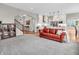 Open-concept living space with a red leather sofa, seamlessly connecting to a modern white kitchen and staircase at 10603 Hinterland Dr, Fishers, IN 46038