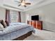 Bedroom with a tray ceiling, large window, and a wooden dresser with TV at 10603 Hinterland Dr, Fishers, IN 46038