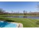 Scenic backyard view with a swimming pool, lush green lawn, pond, and golf course in the background at 11050 Midnight Pass, Fishers, IN 46037