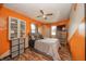 Bright bedroom with orange accent wall, ceiling fan, laminate floors, and natural light at 16371 State Road 38 E, Noblesville, IN 46060