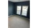Bedroom featuring carpet, navy-blue walls, base trim, and two large windows at 2250 N Pennsylvania St # 8, Indianapolis, IN 46205