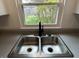 Close up of a stainless steel kitchen sink with a modern faucet and view to the yard at 265 Bittersweet Dr, Whiteland, IN 46184