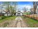 Full view of exterior, featuring gravel driveway, grassy yard, and wooden fence at 2915 E 19Th St, Indianapolis, IN 46218