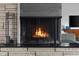 Detailed view of a stone fireplace with a visible flame and fireplace tools at 315 Sunset Dr, Columbus, IN 47201