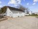 Three-door garage with attached white building sits on large concrete parking area in a rural setting at 3308 S 600 E Rd, Waldron, IN 46182