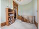 A carpeted hallway with an oak bookcase, detailed trim, and a wooden staircase adds vintage charm at 3308 S 600 E Rd, Waldron, IN 46182