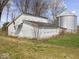 A white outbuilding sits on green grass, next to a metal silo and smaller building, beneath a blue sky at 3308 S 600 E Rd, Waldron, IN 46182