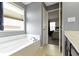 Bright bathroom featuring a large soaking tub, window view, and gray walls, leading to the primary bedroom at 3511 Limesprings Ln, Whitestown, IN 46075
