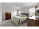Light-filled bedroom features a ceiling fan, plush carpeting, and a comfortable queen-sized bed with light green covers at 3511 Limesprings Ln, Whitestown, IN 46075