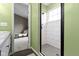 Modern bathroom features tiled shower, open doorway, sleek vanity, and green walls at 3724 W 42Nd Ter, Indianapolis, IN 46228
