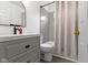 Bright bathroom with a gray vanity, round mirror, and a shower with gray tile and curtain at 3724 W 42Nd Ter, Indianapolis, IN 46228