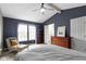 This is a primary bedroom with gray walls, a ceiling fan, a chair, and a large window at 3724 W 42Nd Ter, Indianapolis, IN 46228