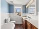 Bathroom featuring a soaking tub, blue walls, and vanity with wood cabinetry at 5116 Norway Dr, Indianapolis, IN 46219