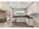 Functional kitchen with white cabinets, stainless steel appliances, a ceiling fan, and neutral tile backsplash at 5116 Norway Dr, Indianapolis, IN 46219