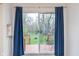 View of the deck and backyard through the sliding glass door, with blue curtains at 5734 Hillside Ave, Indianapolis, IN 46220