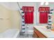Cozy bathroom with a tub/shower, single sink vanity, and colorful red and blue window treatments at 5734 Hillside Ave, Indianapolis, IN 46220