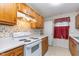 Functional kitchen with wood cabinets, white appliances, and checkered window treatment at 5734 Hillside Ave, Indianapolis, IN 46220