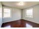 A naturally-lit bedroom with painted walls, dark-stained hardwood flooring, and two bright windows at 6047 W 56Th St, Indianapolis, IN 46254