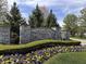 Stone entrance to Whispering Pines community with manicured landscaping and flower beds displaying beautiful yellow and purple pansies at 6071 Sugar Pine Dr, Avon, IN 46123