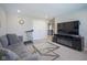 Inviting living room with a gray couch, glass table, large TV, and a treadmill, offering comfort and entertainment at 7140 Leatherwood Dr, Indianapolis, IN 46259