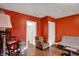 Bright living room featuring hardwood floors, a futon, decorative rug, and a vibrant red accent wall at 725 N Sheffield Ave, Indianapolis, IN 46222