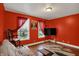 Bright living room featuring hardwood floors, a futon, decorative rug, and a vibrant red accent wall at 725 N Sheffield Ave, Indianapolis, IN 46222