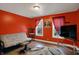 Bright living room featuring hardwood floors, a futon, decorative rug, and a vibrant red accent wall at 725 N Sheffield Ave, Indianapolis, IN 46222