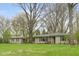 A home featuring a stone facade, green shutters, and a sprawling front yard under large trees at 7575 Holliday W Dr, Indianapolis, IN 46260