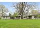 Charming single story home featuring a stone facade, green shutters, and a sprawling front yard at 7575 Holliday W Dr, Indianapolis, IN 46260