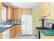Kitchen featuring light wood cabinets, green countertops, tile backsplash, and white appliances at 7575 Holliday W Dr, Indianapolis, IN 46260