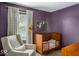 Charming bedroom featuring a deep purple accent wall, comfortable seating, and vintage furniture at 7914 Cardinal E Cv, Indianapolis, IN 46256