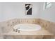 Bathroom features an oval soaking tub with silver hardware, beige tile surround, and white walls at 9769 Marina Village Dr, Indianapolis, IN 46256