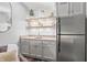 Charming wet bar featuring custom shelving, granite countertops, stainless steel refrigerator, and modern fixtures at 9769 Marina Village Dr, Indianapolis, IN 46256