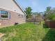 A fenced backyard featuring a brick exterior, lush green grass, and mature trees in the distance at 9831 N Port Dr, McCordsville, IN 46055
