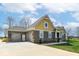Side exterior view with a three car garage and beautiful brick and vinyl siding details under a clear blue sky at 10151 E 191St St, Noblesville, IN 46060