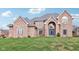 A brick two-story home with a blue front door and arched entryway is nestled in a lush green yard at 10157 Woods Edge Dr, Fishers, IN 46037