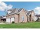 A two-story brick home boasts a three-car garage, mature landscaping, and lush green lawn at 10157 Woods Edge Dr, Fishers, IN 46037