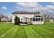 Wide shot of home's backyard featuring a well manicured lawn, patio, and sun room at 10234 Leeward Blvd, Indianapolis, IN 46256