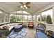 The sunroom has a wood floor, a ceiling fan, a wicker sofa, and natural lighting at 10234 Leeward Blvd, Indianapolis, IN 46256