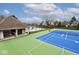 Well-maintained tennis court with a bright blue playing surface and green surroundings, perfect for recreational play at 10234 Leeward Blvd, Indianapolis, IN 46256